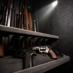A dimly lit gun safe with neatly arranged firearms on shelves